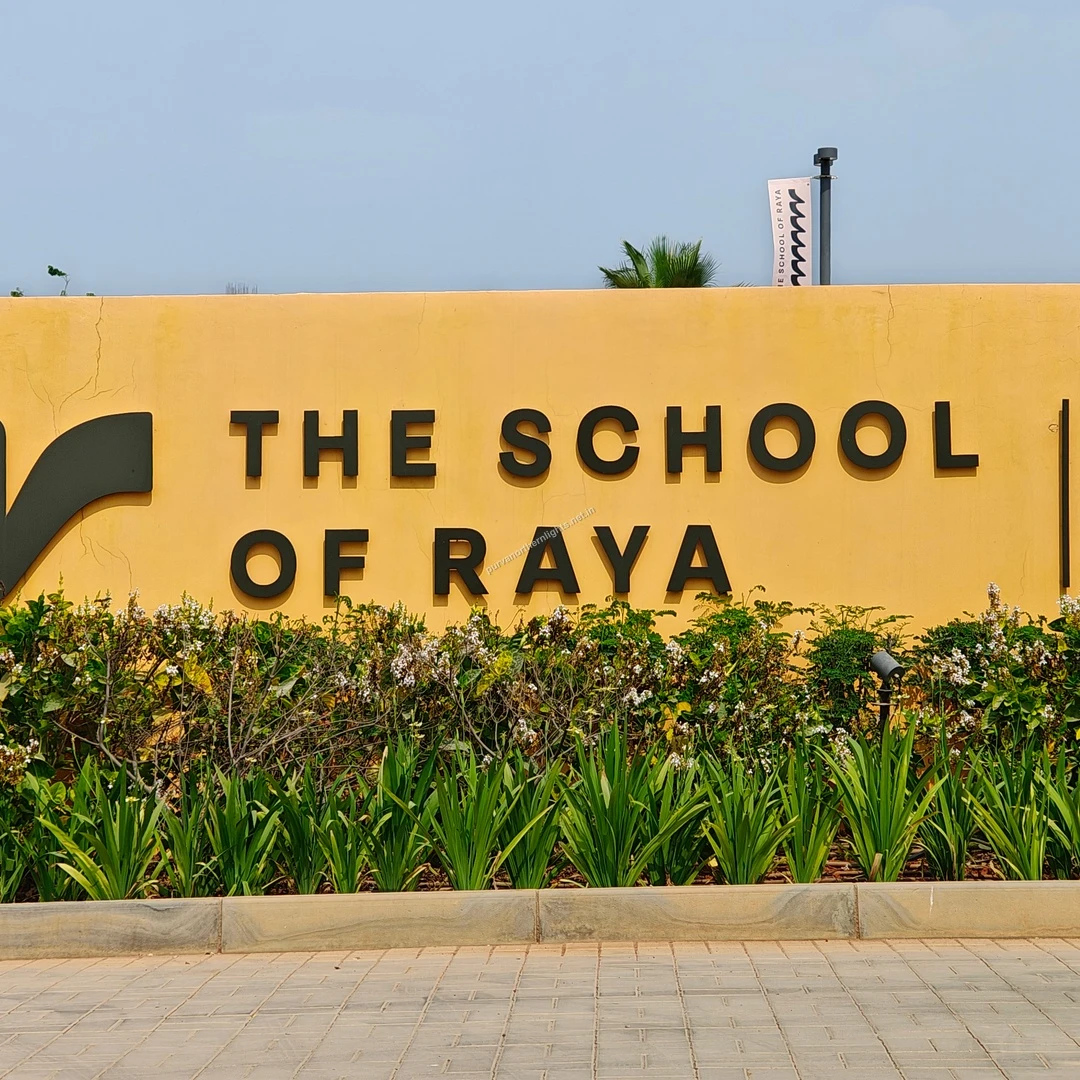 School of Raya Wall The bright yellow exterior boundary wall featuring bold black lettering for The School of Raya, surrounded by manicured plants.