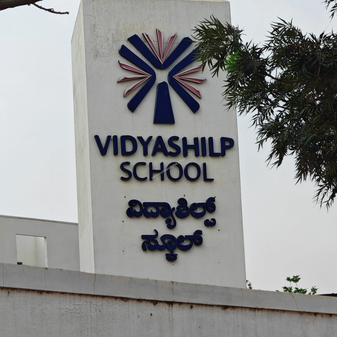 Vidyashilp Pillar Sign The tall white entrance pillar of Vidyashilp School featuring its colorful emblem and bilingual text near the project site.